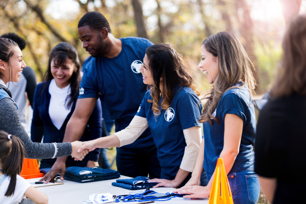 group of volunteers shake hands at a community event outside