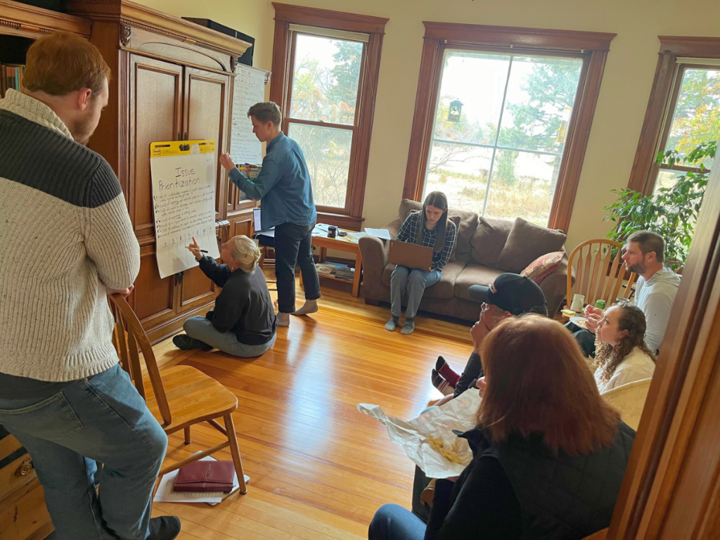 A group of community members brainstorm ideas together while HEJC program manager Chris Reimer writes ideas down on a notepad.
